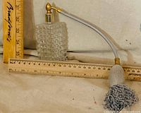 Overall view of cut-glass perfume atomizer with measuring rulers for scale