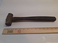 Full view of steel mallet beside ruler for scale