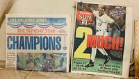 Front view of both newspapers showing championship headlines and dates