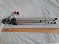 Collapsed aluminium tripod beside 24 in. ruler showing size and features