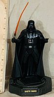 Front view of Darth Vader figurine showing lightsaber, armor and nameplate on base with ruler for scale
