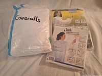 Three packages of coveralls: two sealed retail packages, one clear bag with opened pair