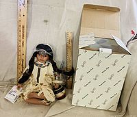 Full view of doll seated with accessories and original box