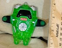 Top view of green Fisher-Price Imaginext vehicle next to ruler for scale
