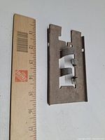 Metal wall-mount flag pole bracket beside ruler for scale