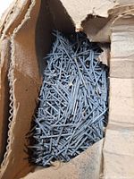 Open carton showing quantity of loose galvanized finishing nails
