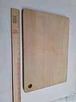Rectangular hardwood cutting board beside ruler for scale