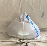 Silver Hershey’s Kisses pillow with white plume tag