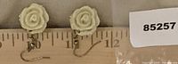 Close-up of both rose earrings beside ruler showing size