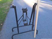 Pair of black metal folding table leg frames with yardstick indicating height