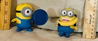 Both Minion figurines side by side with rulers for scale