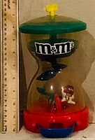 Full frontal view showing M&M's logo, hourglass shape, ruler indicating height