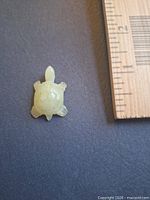Top view of small pale green onyx turtle beside ruler showing ~1.25 inch length