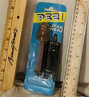 Front view of sealed Chewbacca PEZ dispenser on Star Wars card between rulers for scale