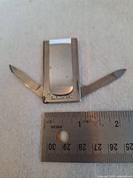 Folding cutter open showing two blades, belt clip and Barlow B60 stamp with ruler for scale