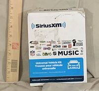 Front view of SiriusXM Universal Vehicle Kit retail box with ruler for scale