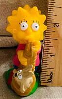 Front view of Lisa Simpson figurine beside ruler showing height