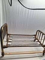 Side view of brass doll bed showing full frame and spring base with ruler indicating size
