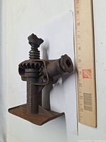 Full view of jack next to ruler for scale, showing gear mechanism, screw post, base