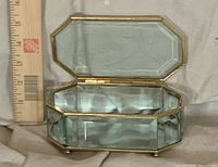 Jewelry box open showing interior mirror and gold frame next to ruler for scale