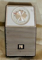 Front view of PM transistor radio showing grille, logo, tuning dial