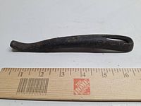 Full view of cast iron wood stove lifter beside ruler showing length