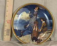 Front view of plate showing artwork and gold rim beside ruler