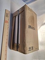 Closed box labeled Mosa with strapping and ruler for scale