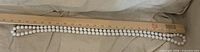 Entire necklace beside ruler showing length and round white beads