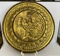 Embossed brass wall charger with tavern scene and floral rim