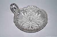 American Brilliant style nappy dish showing starburst and hobstar cuts, loop handle