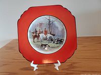 Front of Wedgwood fox hunt plate showing red border and hunting scene