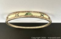 Full view of hinged silver bangle showing enamel panels and cutouts