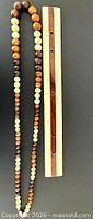 Graduated wood bead necklace beside ruler showing bead sizes