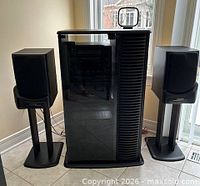 Front view of cabinet with glass door flanked by two speakers on stands