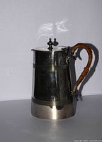 Left side view showing tapered form, banding, finial, wicker handle