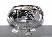 Side view of clear glass three-footed bowl with sterling silver overlay