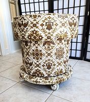 Side view of ottoman showing tapestry fabric and casters