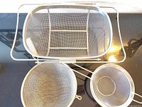 Top view showing all three stainless steel mesh strainers: rectangular basket and two round handled strainers