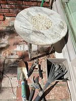All items in lot: rustic round table and assorted garden tools laid out