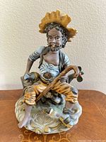 front view of ceramic figurine man seated on log