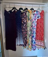 Six dresses hanging on closet rod showing full assortment