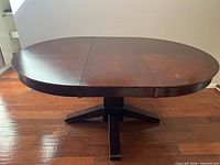 Full view of dark wood oval dining table with leaf inserted