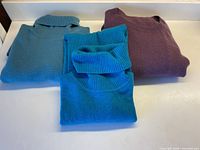 All three folded sweaters displayed together