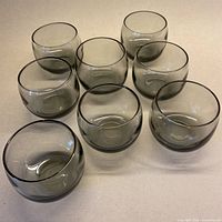 Eight smoky grey roly poly glasses grouped on surface