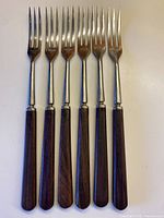 All six forks front view showing stainless steel tines and walnut handles