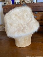 Side view of blond mink fur hat on stand