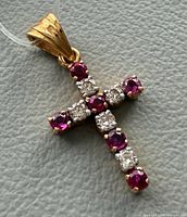 Front view of gold cross pendant showing gemstones arrangement