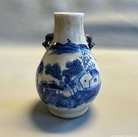 Front view of blue & white crackle glaze vase with landscape scene and foo dog handles