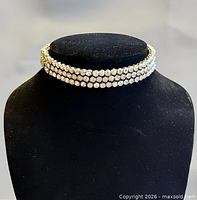 Choker displayed on black bust showing triple rows of rhinestones